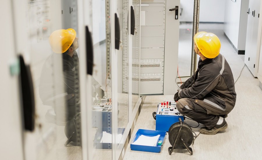 Electrician engineer tests system with relay test set equipment